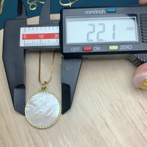 Detail view of a gold-plated round mother-of-pearl pendant necklace with box chain.