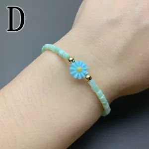 Detailed shot of a simple shell beaded bracelet featuring a cute blue daisy flower charm.