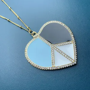 Primo piano dettagliato della grande collana con cuore, simbolo di pace e zirconi.