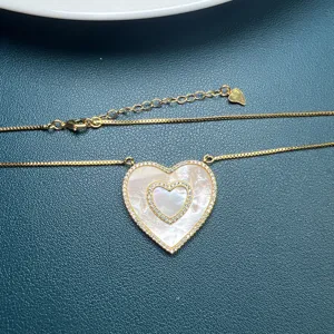 Primo piano dettagliato della collana con ciondolo a doppio cuore dorato con madreperla.