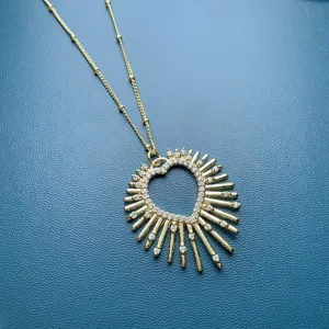 Primo piano di una collana con ciondolo a cuore sole placcato in oro con zirconi lucidi.
