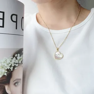 Dettaglio della collana con ciondolo a cuore in madreperla e catenina perlata dorata.