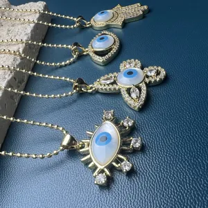 Gold hamsa hand evil eye butterfly necklace set with white shell and sparkling crystal stones.
