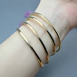 Detailed view of stackable gold metal open bangles worn on wrist for women fashion jewelry.