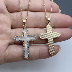 Gold cross necklace detail featuring white mother of pearl and colorful cubic zirconia stones.