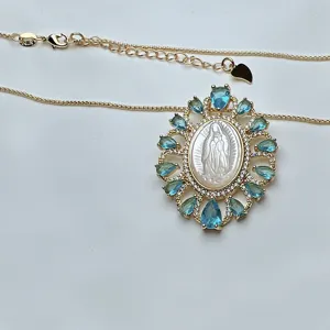 Primer plano del collar bañado en oro con colgante de nácar blanco y circonitas azules.