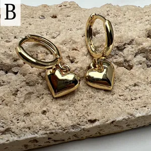 Vista detallada de elegantes pendientes de aro dorados con elegantes colgantes de corazón.