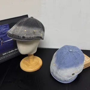 Vintage Farbverlauf Denim Schiebermütze Detail zeigt Farbspritzer und Metallabzeichen.