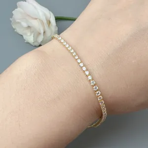 Minimalist adjustable gold-toned tennis bracelet sparkling with dainty clear cubic zirconia.