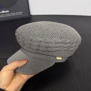 Detailed view of the stylish grey knitted newsboy cap featuring a chic metallic side accent.