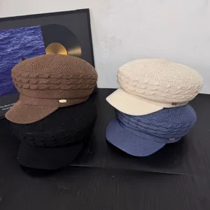 Detailed view of stacked retro knitted newsboy caps in various classic colors with metal logo accents.
