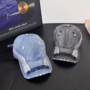 Distressed denim baseball cap with angel wings embroidery and trendy streetwear style text.