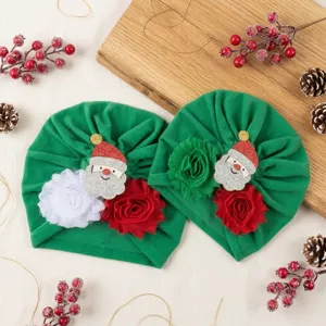 Detailed view of the Christmas baby turban hat featuring festive Santa and fabric flower accents.