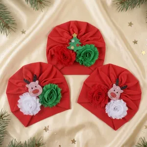 Detailed view of adorable baby Christmas red turban hats with festive floral and reindeer decor.
