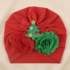 Close-up detail of the red baby turban hat featuring a sparkling Christmas tree and fabric flowers.