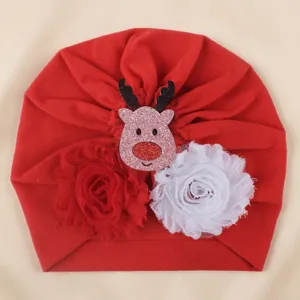 Red baby turban hat featuring cute Christmas reindeer and dual flower decorations.