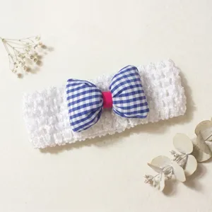 Close-up of cute baby hairband with blue checkered bow on white crochet elastic band.