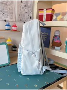 Side detail view of light blue polka dot backpack with plaid pocket and drawstring.