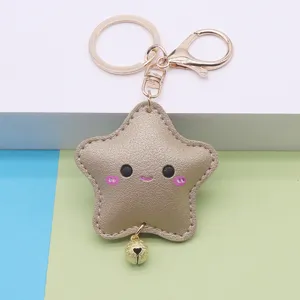 Close-up detail of the cute gold star PU leather keychain with a smiling face and bell.