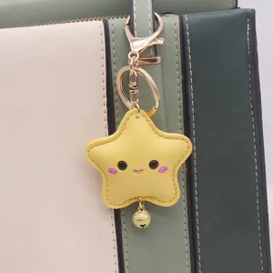Close-up detail of a cute yellow PU leather star keychain with a smiling face and a tiny bell.