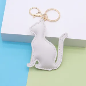 White PU leather cat keychain detail view, cute bag charm with gold metal hardware.