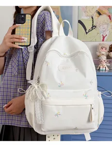 Detail shot of sweet white backpack featuring colorful embroidered bows and delicate lace pearl pendant.