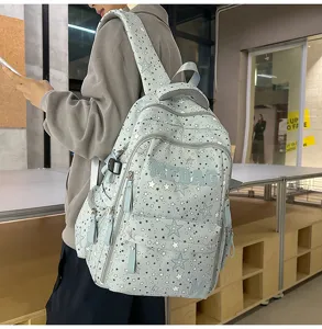 Detailed view of the light blue star-patterned backpack worn by a model in a studio setting.