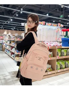 Vista dettagliata del grazioso zaino rosa da studente con fiocchi decorativi e ricami frontali.