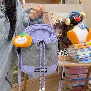Close-up detail of the purple and grey grid bucket bag with cute plush pendant for travel.