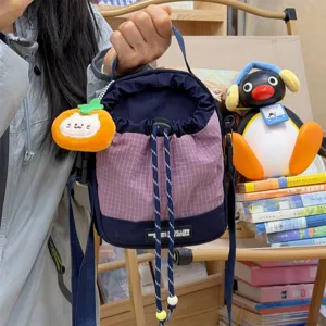 Detail shot of purple grid drawstring bucket bag with orange plush pendant for casual outdoor use.