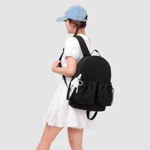 Vista detallada de una mochila escolar ligera negra con bolsillo frontal fruncido con cordón.