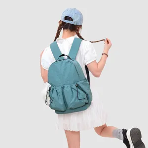Vista detallada de la mochila azul ligera llevada por la modelo con bolsillo con cordón.
