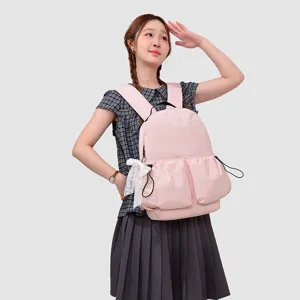 Detalle de mochila de estudiante rosa claro con bonito lazo de encaje blanco y bolsillos.