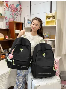 Black canvas backpack with green clover embroidery and cute tulip pendant for daily use.
