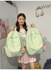 Detail view of the lime green clover embroidered backpack showing front pocket and straps.