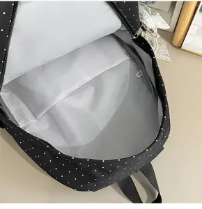 Black and white polka dot backpack interior detail, casual school bag storage design.