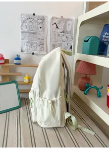 Minimalist off-white backpack with soft green straps and drawstring side pockets detail.