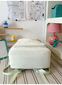 White canvas backpack with cute light green four-leaf clover embroidery, detail view.