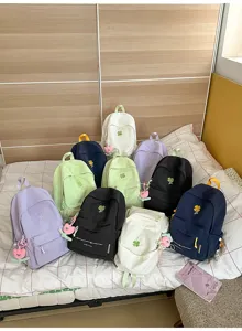 Detailed view of multiple casual backpacks with clover embroidery and cute tulip keychains.