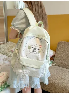 Backpack detail view showcasing polka dot pattern, lace bow charm, and soft pastel green tone.
