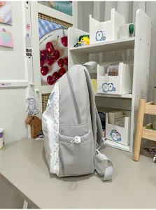 Sac à dos à pois gris et blanc vue latérale, sac décontracté étudiant avec poches et bretelles.