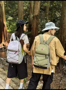 Outdoor couple hiking backpacks shown in forest scene, lightweight drawstring design.