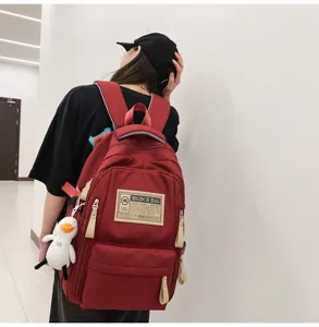 Red canvas backpack detail featuring front pockets, durable fabric and a cute duck pendant.
