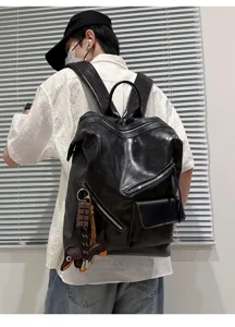Detailed back view of the black leather backpack showing the retro zipper design and charms.