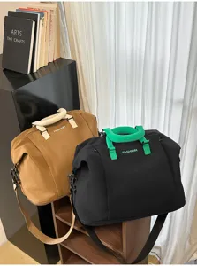 Vista detallada de bolsa de viaje deportiva grande colorblock con asas y correa contrastantes.