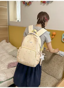 Close-up detail of the sweet yellow star pattern backpack worn by model in cozy bedroom.