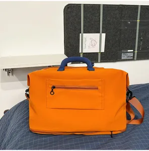 Dettaglio borsa da viaggio arancione con tasca frontale, manico blu e struttura resistente.