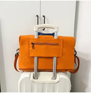Borsa da viaggio arancione con dettaglio fascia per valigia, ideale per brevi viaggi e palestra.