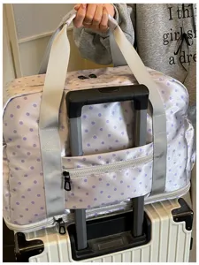 Detailed view of a purple polka dot travel duffel bag with trolley sleeve and expandable base.