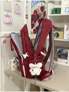 Detailed view of red school backpack with cute plush bear pendant, sweet college style.